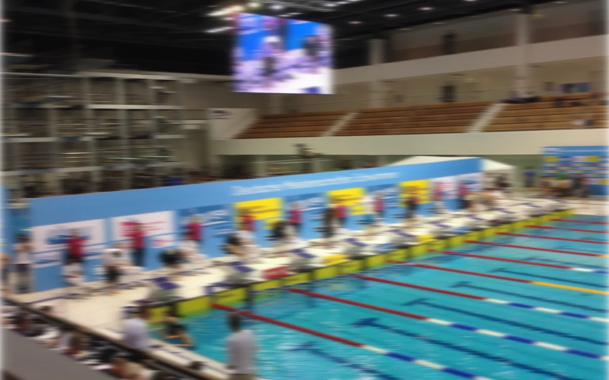 A competition pool during a swim meet, lanes busy with swimmers